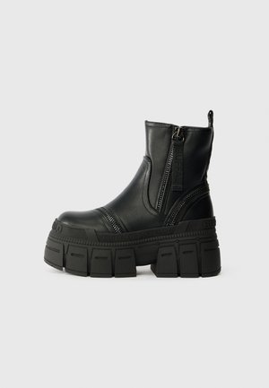 Botas de tornozelo pretas feitas de couro liso, com sola plataforma grossa, fecho éclair frontal e detalhes de costura texturizada.