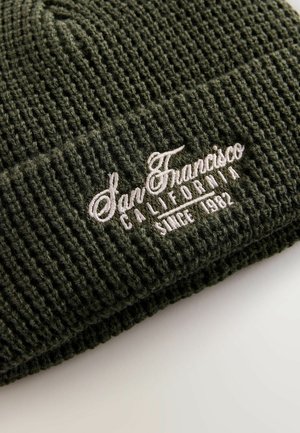 Cappellino in maglia verde con texture a coste, con ricamo bianco che recita "San Francisco California Dal 1982."