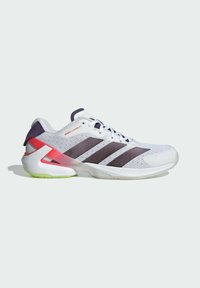 Chaussure de sport blanche avec des rayures noires, un support de talon rouge, une semelle néon verte et un dessus en maille pour la respirabilité.