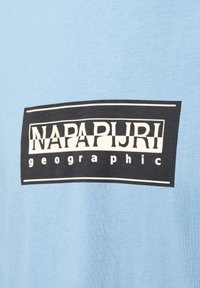 Hellblaue Baumwoll-T-Shirt mit einem schwarzen rechteckigen Logo, auf dem der Text "NAPAPIJRI geographic" in Weiß steht. Glatte Textur, lässige Passform.