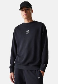 Felpa nera con collo e polsini a costine, con logo New York Yankees ricamato in bianco sul petto e pantaloni da jogging abbinati.