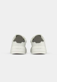 White sneakers with dark gray heel tabs, thick white soles, and "Replay" branding embossed on the back of each shoe.