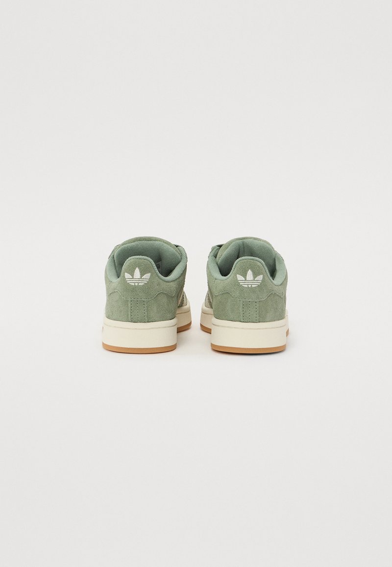 Zapatillas de ante verde con suela de goma blanca. Presentan un acabado texturizado, puntera redonda y un logo en el talón. Detalles de diseño sutiles.
