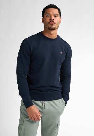 Navy long-sleeve sweatshirt with a crew neckline and ribbed cuffs, featuring a small emblem on the chest. Smooth fabric texture.
