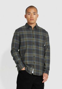 Groen en zwart geruite shirt met blauwe accenten, voorzien van een knoopsluiting, een enkele borstzak en een structuurstof.