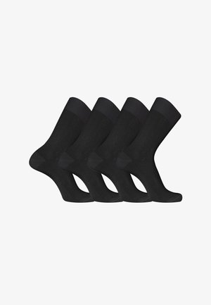 Quatre paires de chaussettes noires longueur mollet, alignées en rangée avec un pied légèrement relevé et des bords-côtes.