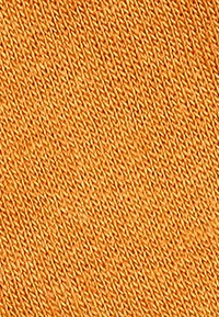 Strikket stof i en livlig orange farve, der viser et struktureret mønster med diagonale striber. Teksturen ser blød og jævnt vævet ud.