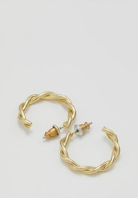 Gold twisted hoop earrings featuring a metallic finish, accented with wooden posts and silver-toned hardware. Notable twisted design.