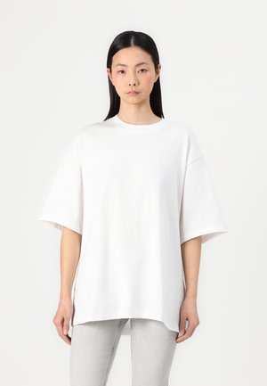 Overmaat wit katoen T-shirt met korte mouwen, ronde hals en een gebogen zoom. Eenvoudig ontwerp, zachte textuur en een comfortabele pasvorm.
