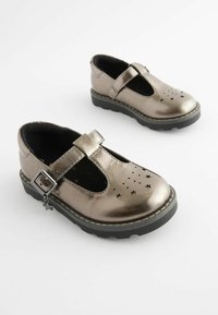 Metallisch silberne Mary Jane-Schuhe mit perforiertem Sternmuster, verstellbarem Riemen mit Schnalle, schwarzen Gummisohlen und runder Zehenform.