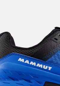 Nærbillede af hælen på en blå og sort Mammut sportssko med tekstureret stof og detaljer i gummiydersål.