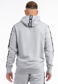Gray hoodie with a hood, featuring black side stripes with text. Soft texture, elastic cuffs, and a relaxed fit.