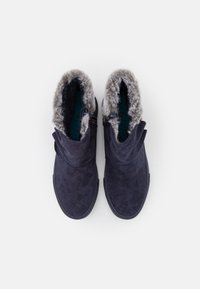 Botas de tornozelo em camurça azul-escuro com forro em pelo sintético, design descontraído, bico arredondado e hardware minimalista. Adequadas para uso casual.