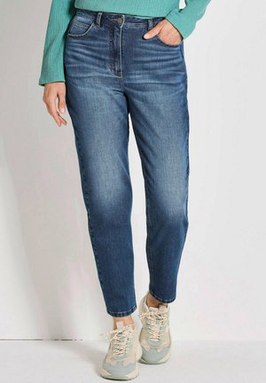 Jeans in denim a vita alta di colore blu scuro con una vestibilità dritta, con tasche anteriori e chiusura con bottone classico. Indossati con scarpe da ginnastica beige.