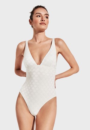 Traje de baño de una sola pieza blanco con un escote en V profundo, textura de puntos, tirantes anchos y piernas con corte alto, confeccionado con una tela suave y elástica.