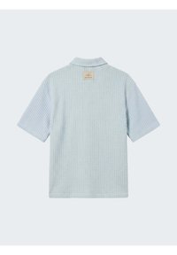 Chemise bleu clair à manches courtes avec texture gaufrée et col, vue de dos avec une petite étiquette beige près de l'encolure.