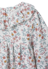 Weißer Stoff mit pinken und gelben Blumenmustern sowie blaugrünen Blättern, mit einem gerafften Ausschnitt und Rüschendetail am Kragen.