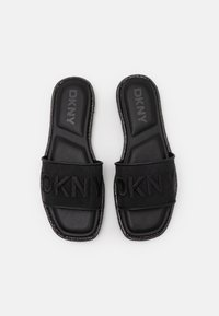 Black DKNY slide sandals with a textured fabric upper, featuring a bold logo, cushioned insole, and decorative beaded trim.
