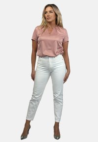 Pink satin short-sleeve top with a keyhole design, paired with white high-waisted jeans and snakeskin-patterned heels.