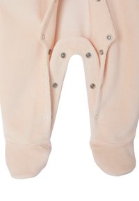 Pfirsichfarbenes Baby-Overall mit Fußabdeckungen, offenen Druckknöpfen entlang des inneren Beins und der Schrittgegend, die die weiche Stoffstruktur zeigen.