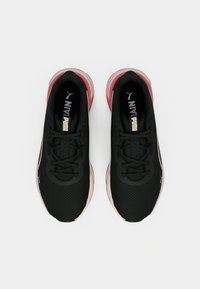 Ζευγάρι μαύρα αθλητικά παπούτσια Puma με ροζ σόλες, από πάνω σε ανοιχτό φόντο.