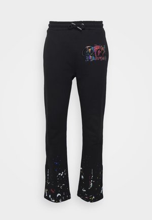 Black sweatpants with a flared cut, featuring a colorful graphic logo on the thigh and paint splatter details at the hem. Cotton blend material.