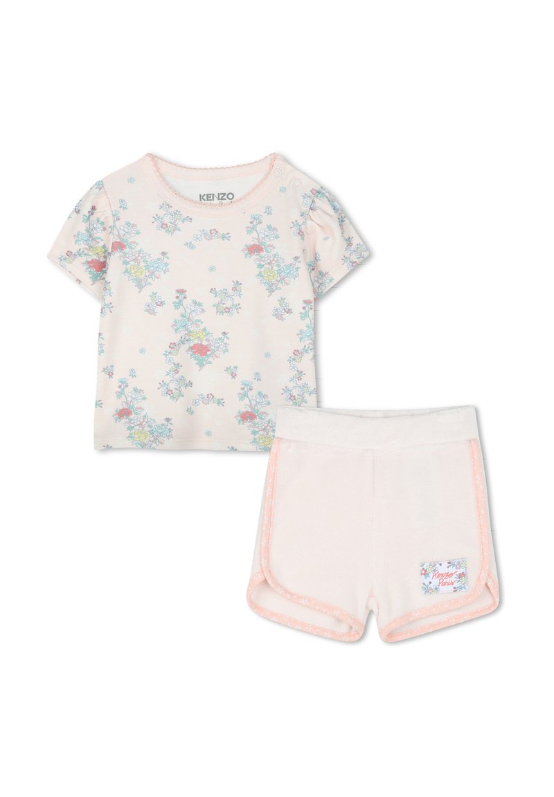 T-shirt à manches courtes, rose clair avec imprimé floral, associé à un short doux et pâle avec des finitions contrastées et une étiquette de marque.