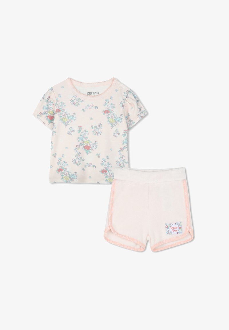 T-shirt à manches courtes, rose clair avec imprimé floral, associé à un short doux et pâle avec des finitions contrastées et une étiquette de marque.
