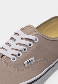 Μπεζ πάνινο παπούτσι Vans με λευκά κορδόνια, λευκές οπές, ορατές ραφές και λευκή λαστιχένια σόλα με μαύρη ρίγα.