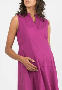 Fuchsia ärmelloses Umstandskleid mit legerem Schnitt, ausgestattet mit einem V-Ausschnitt und Raffung, aus glattem Stoff gefertigt.