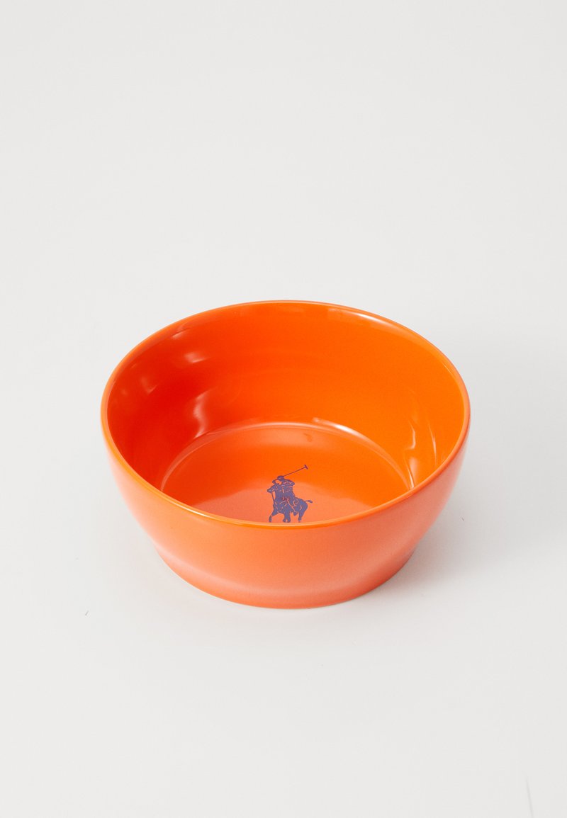 Oranžs plastmasas bļodiņš ar gludu, spīdīgu apdari; iekšējā apakšā ir purpura polo spēlētāja grafika. Apaļa, dziļa forma.
