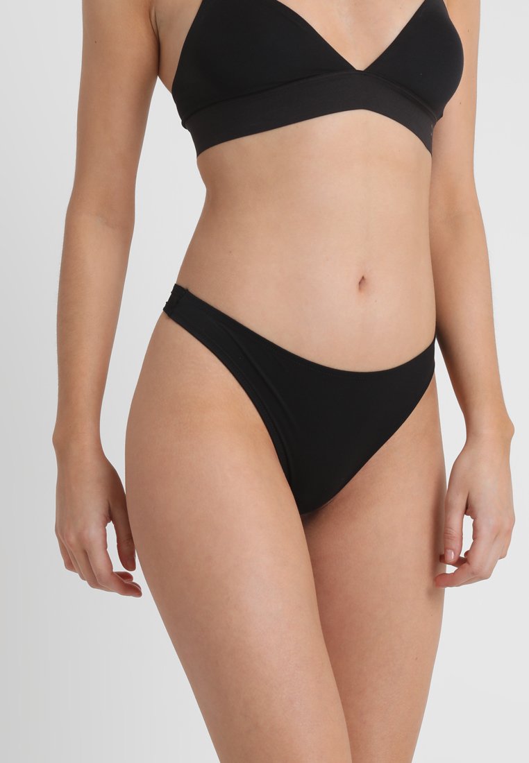 Top bikini nero con design a triangolo e fascia larga, abbinato a slip bikini a vita bassa. Texture liscia e stile minimalista.