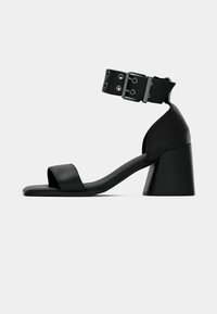 Schwarze Leder High-Heeled Sandale mit einem Knöchelriemen, quadratischer Zehenpartie und einem klobigen, konischen Absatz. Minimalistisches Design mit glatter Textur.