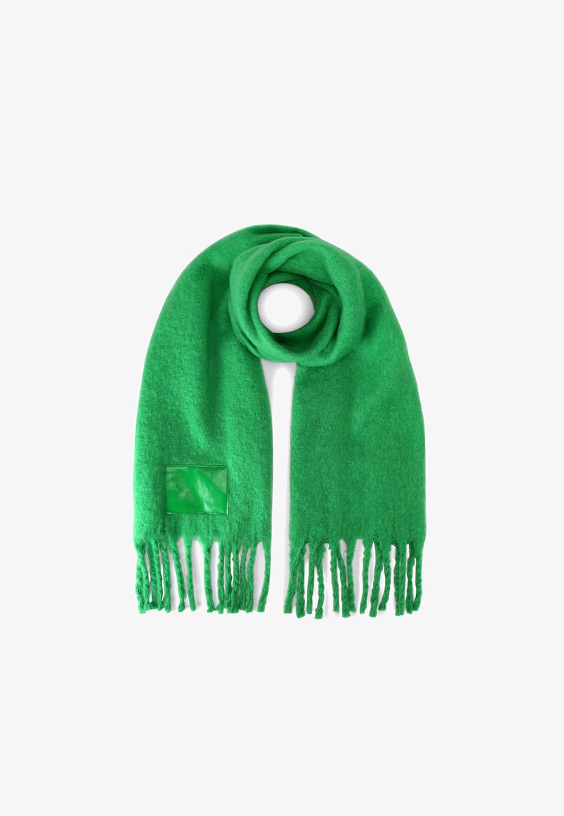Écharpe en laine verte avec des bords effilochés, design circulaire et un accent en cuir carré. Texture douce et couleur vibrante.