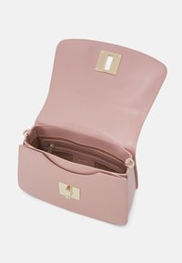 Sac à main en cuir rose ouvert pour montrer une poche intérieure zippée et une fermeture rectangulaire dorée sur fond uni.