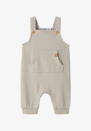Combinaison sans manches beige pour bébé avec bretelles à boutons en bois, poche avant et pressions le long de la couture intérieure pour un change facile.