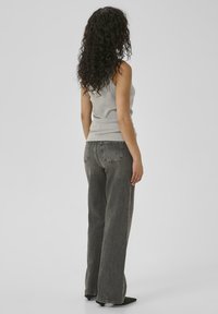 Heledad hallikas tank top, millele on sobitatud vabalt istuvad, pleekinud mustad teksad. Riietus on lihtsa ja sujuva disainiga ning mugava siluetiga.