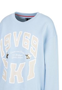Hellblaues Sweatshirt mit auffälliger weißer "1969 SKI" Schrift, dekorativen Pailletten und einem gerippten Kragen mit roten und weißen Akzenten.