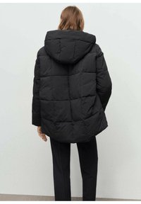 Chaqueta de plumas negra con capucha, que presenta un patrón acolchado, corte holgado y mangas elásticas, vista desde la parte de atrás.