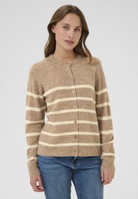 Karamelīgs kardigans ar baltām svītrām, ar apaļu apkakli, pogu aizdari un ribotām aprocēm. Maiga tekstūra, viegla adīta auduma.