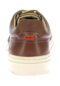 Sneaker in pelle marrone con trama liscia e rivestimento beige, caratterizzato da un logo rosso Kickers sul tallone e una suola in gomma bianca.