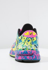 Baskets de course colorées présentant un dessus à motifs en bleu, vert et rose. Comprend un col rembourré noir et des accents jaunes au niveau du talon.