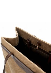Beige woven tote bag with brown leather handles, featuring an open top, inner zip pocket, and a textured fabric surface.