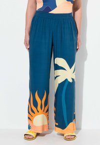 Breda byxor i teal-tyg med tropiska mönster i gult och orange, inklusive solen och palmer. Elastisk midja.
