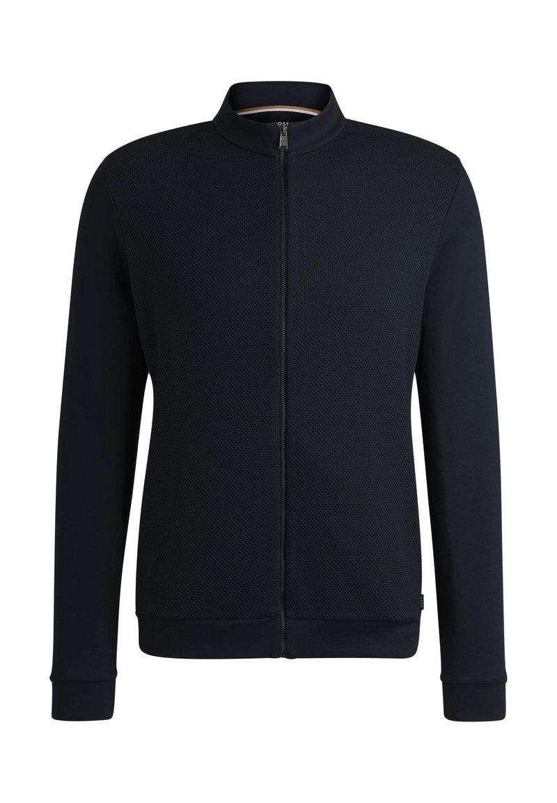 Veste zippée à l'avant en bleu marine uni, fabriquée en tissu texturé. Dotée d'un col montant, de manches longues et de poignets et d'ourlet côtelés.