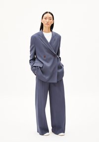Doppelreiher-Blazer und weit geschnittene Hose in Schieferblau, aus strukturiertem Stoff; verfügt über große Taschen und braune Knöpfe.