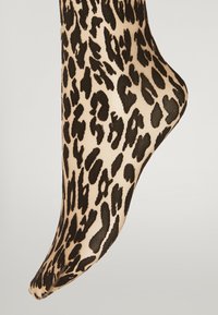Ankelstrømpe med leopardprint, der har en tan-basis med bold sort mønster, glat tekstur og tætsiddende pasform, ideel til afslappet brug.