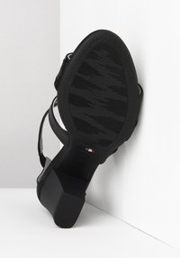 Sorte højhælede sandaler med flere stropper og en tekstureret gummisål. Har en firkantet hæl og detaljer med det italienske flag nær hælen.