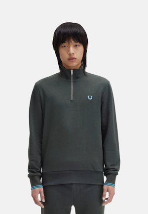 Sudadera de cuello alto de color verde oscuro con una textura suave, que presenta un pequeño logo azul y acentos azules contrastantes en los puños.