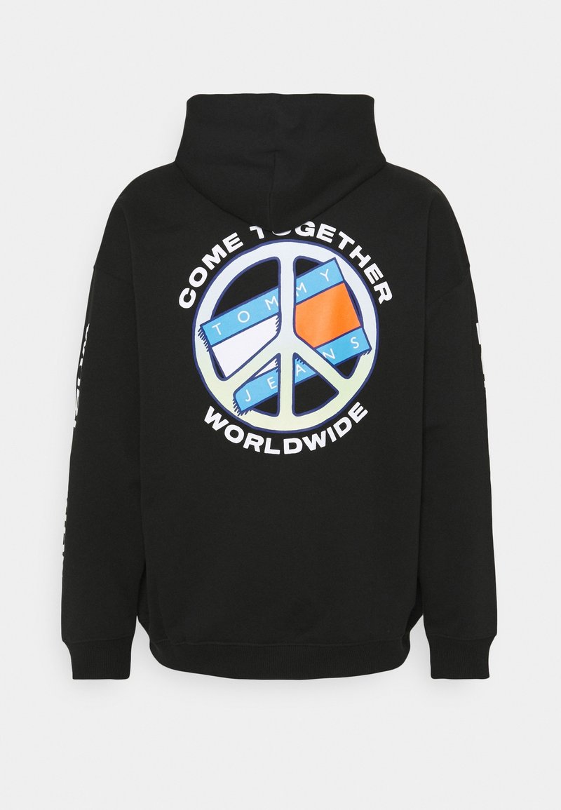 Sudadera negra con capucha que presenta un gran gráfico de símbolo de paz multicolor con el texto "UNÁMONOS EN TODO EL MUNDO" y "TOMMY JEANS" en blanco.